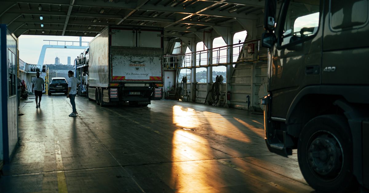 A serene view inside a ferry cargo area with trucks at sunset.